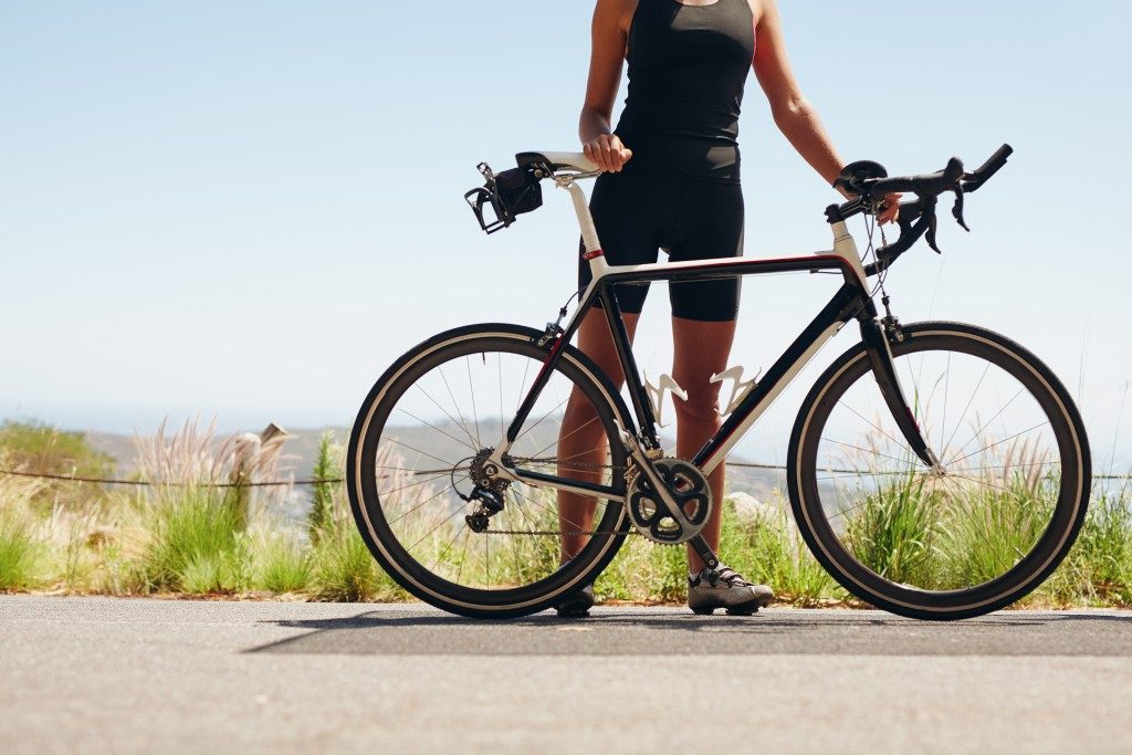 Low section shot of female athlete standing with her bicycle