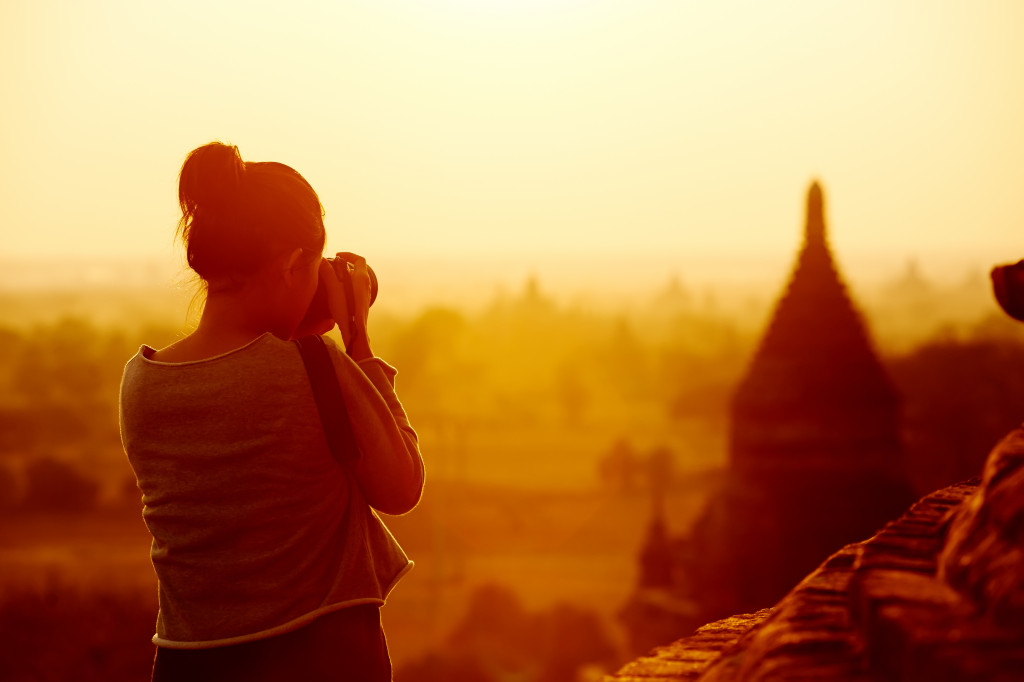 woman capturing the temples in photo during sunrise