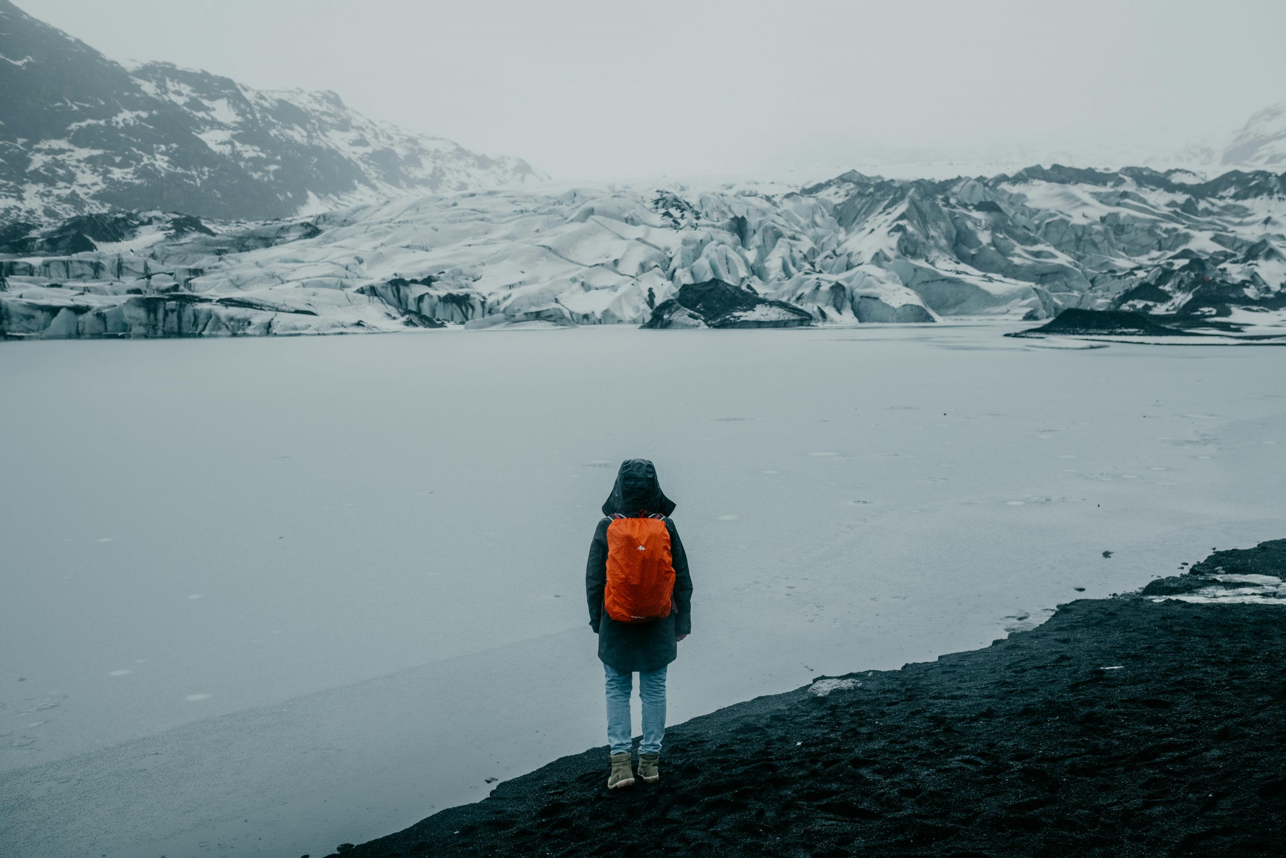 woman with a backpack standing and looking out over a vast snowy landscape in Iceland